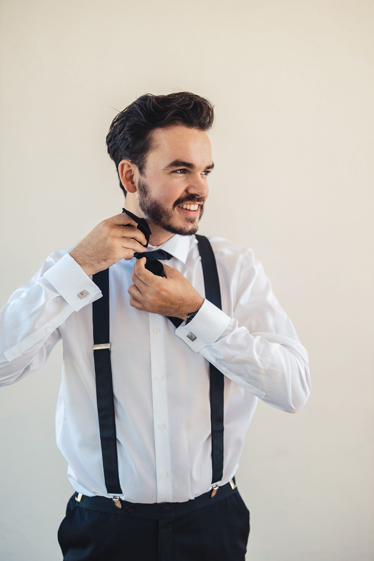 Groom adjusting bow tie during wedding getting ready in Palm Beach Gardens