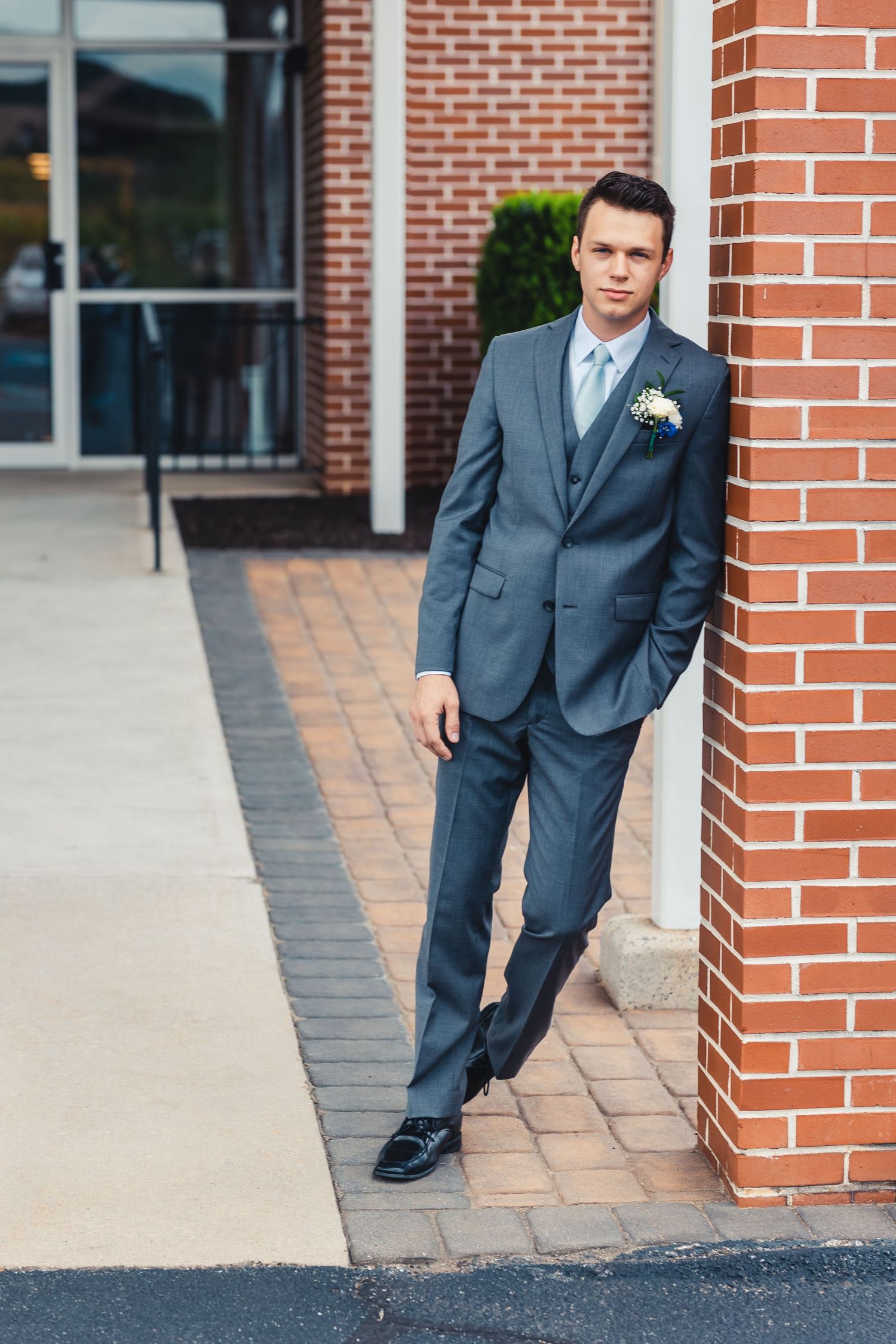 Groom leaning against brick wall during wedding portrait in Palm Beach Gardens