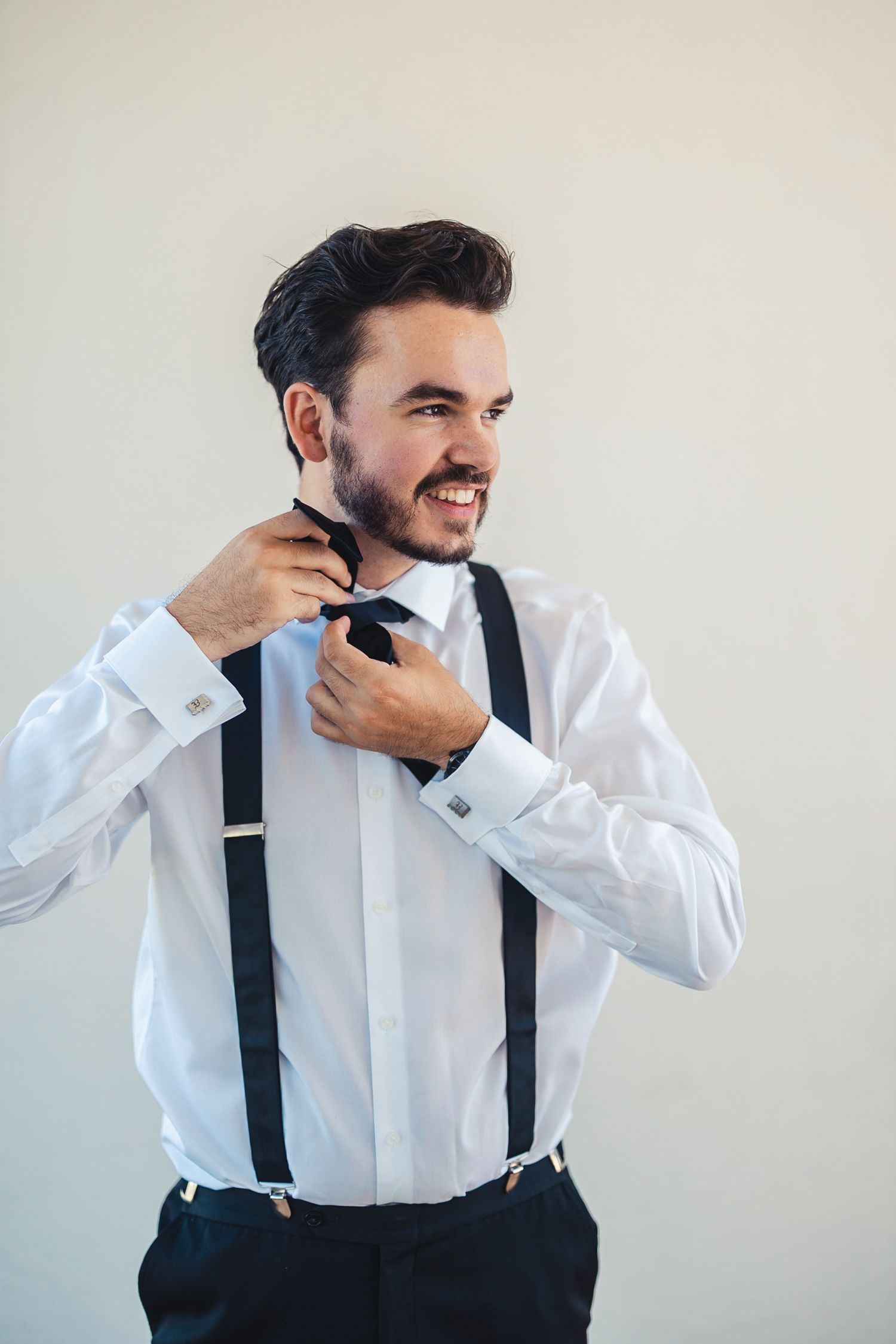 Groom adjusting bow tie during wedding getting ready in West Palm Beach FL