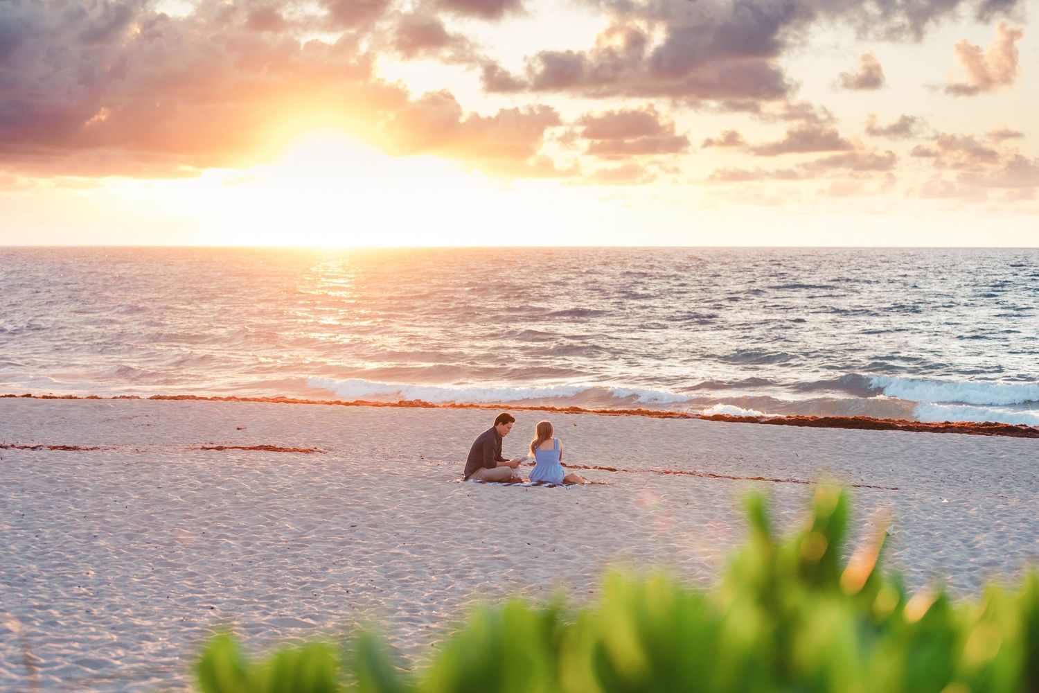 Couple sitting on the beach at sunset during Palm Beach Gardens engagement session