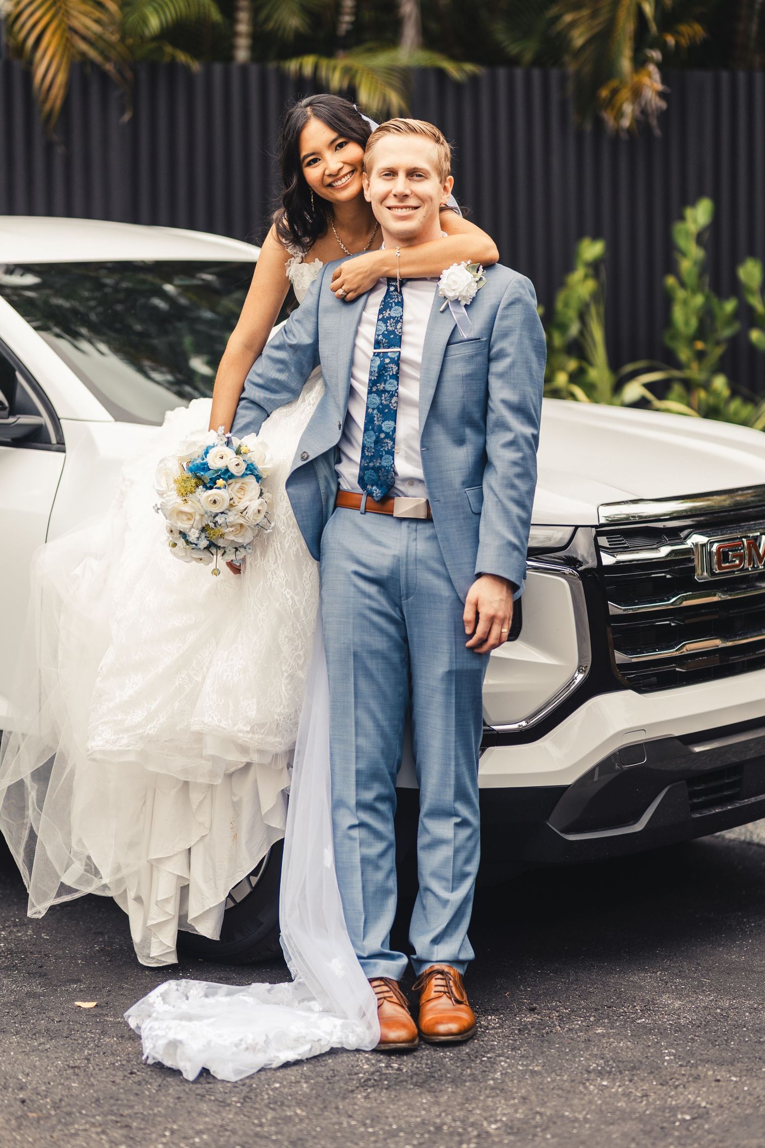 Bride and groom posing by getaway car after Palm Beach Gardens wedding
