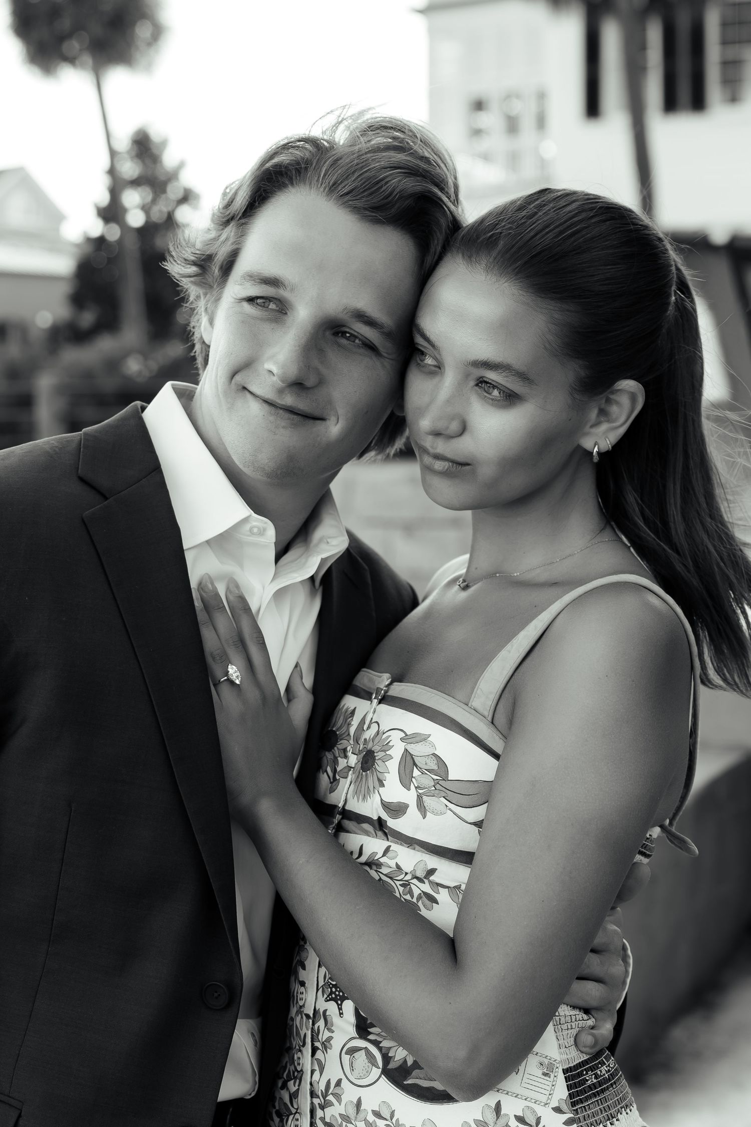Black and white portrait of a happy engaged couple posing together outdoors near historic buildings.
