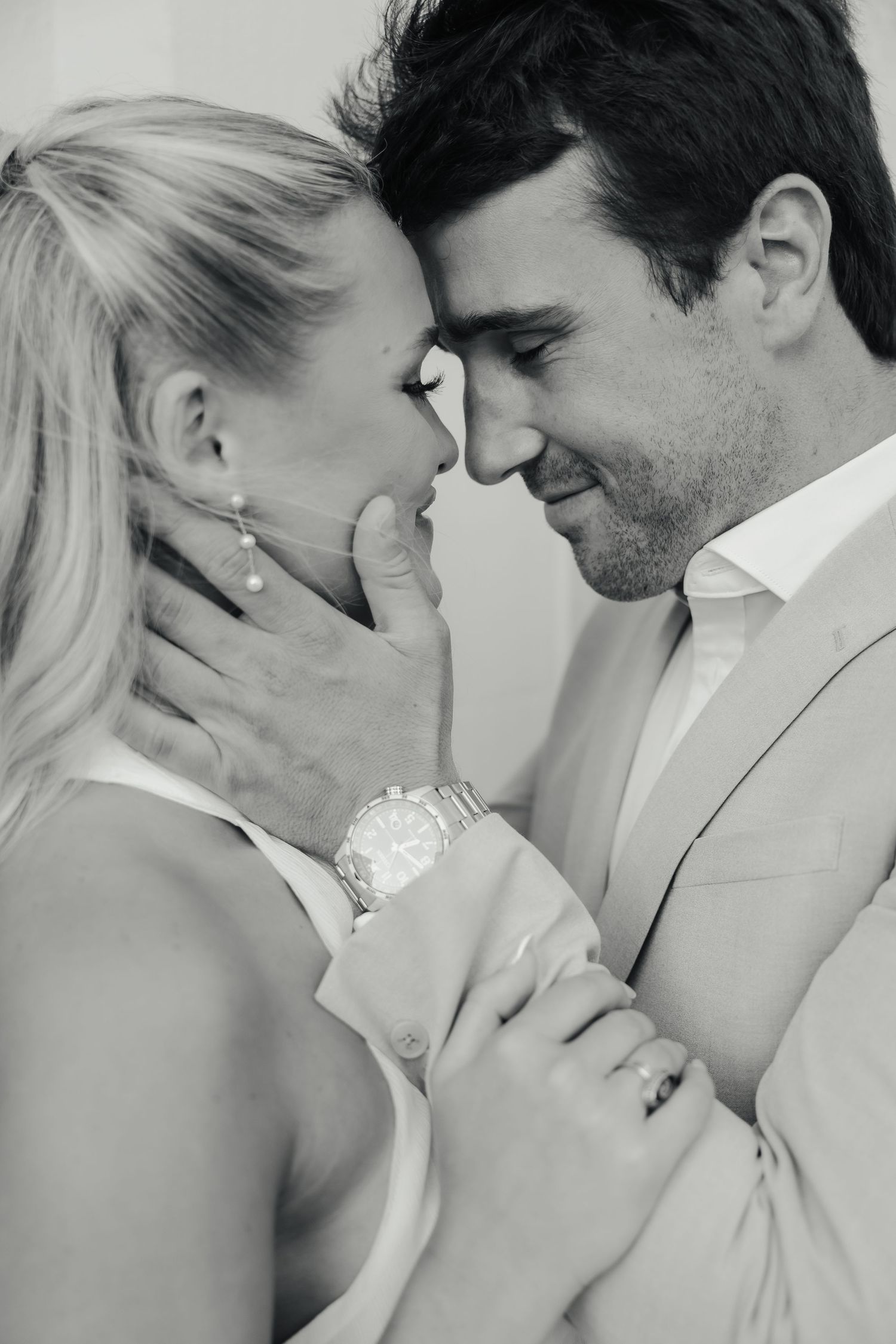 Black and white portrait of bride and groom touching foreheads and smiling tenderly together.