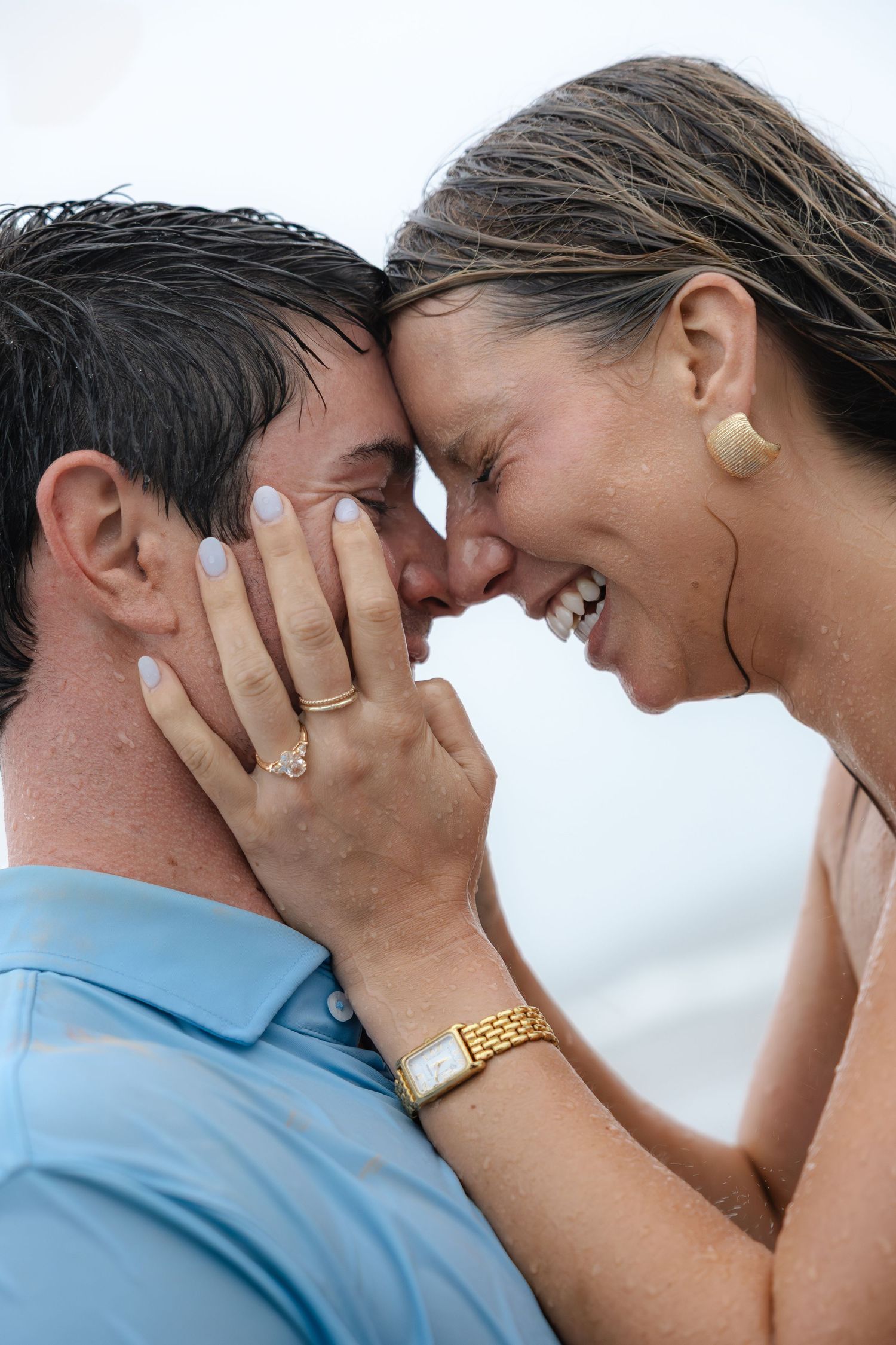 Happy couple sharing a romantic moment, woman wearing engagement ring and gold watch, laughing together outdoors.