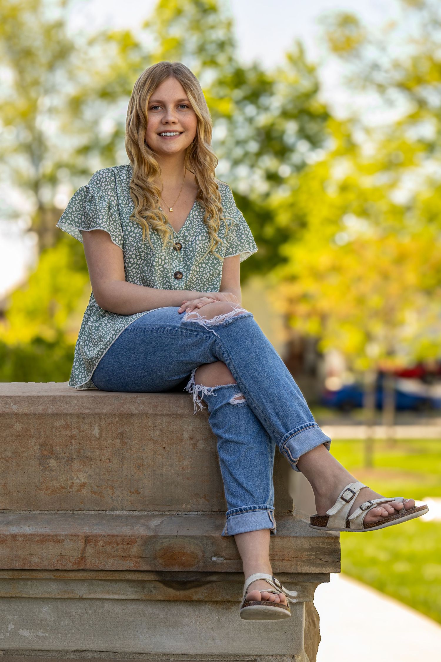 Relaxed outdoor portraits showing someone sitting on a wooden bench in casual spring attire.