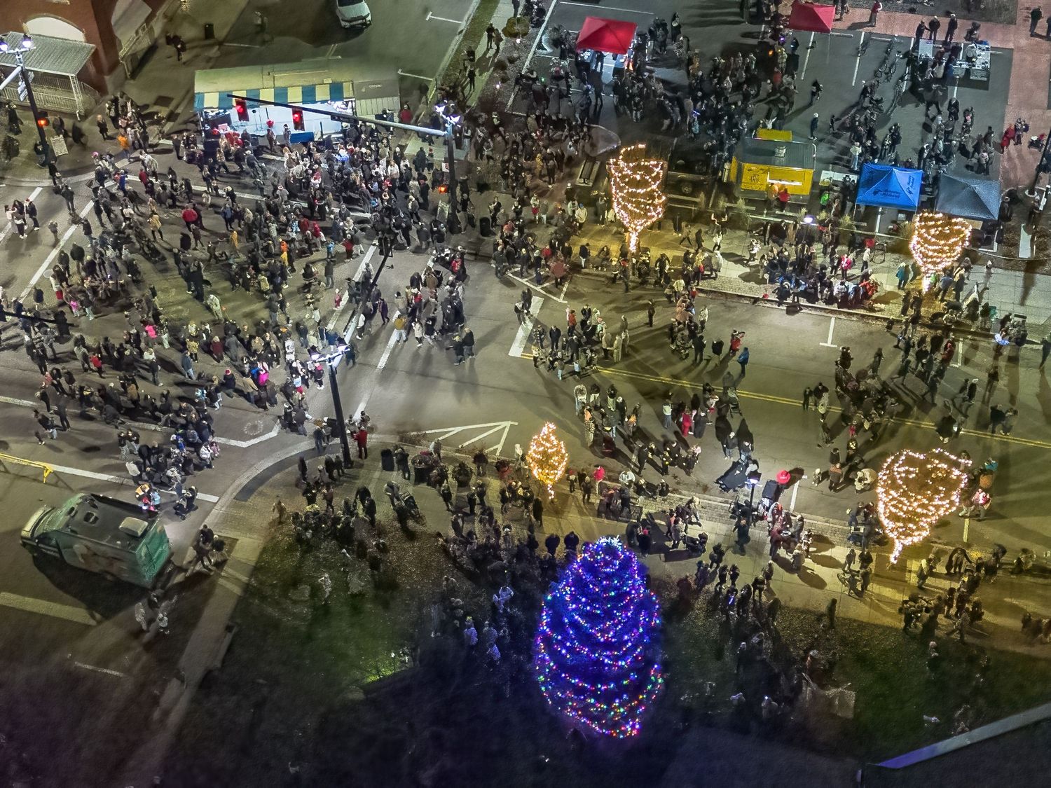 Aerial view of a crowded holiday festival with illuminated trees and decorations.