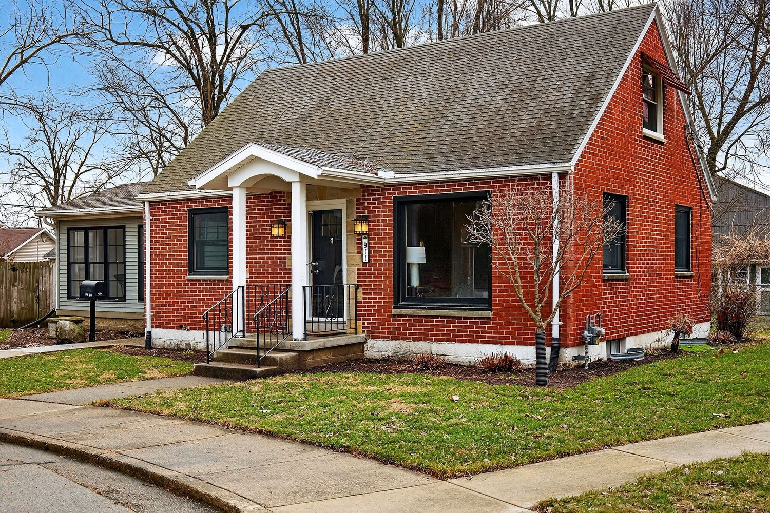 Red brick ranch-style homes with white trim line a residential street on a cloudy day.