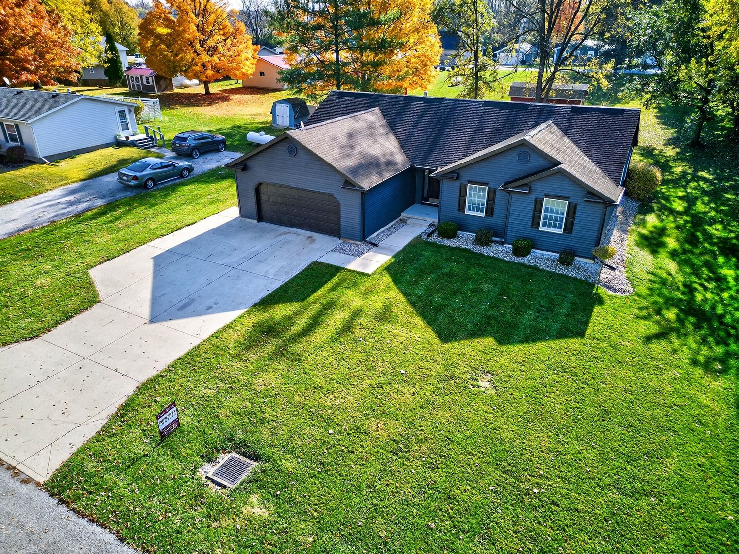 Aerial view of a suburban neighborhood with well-maintained green lawns and driveways during summer.