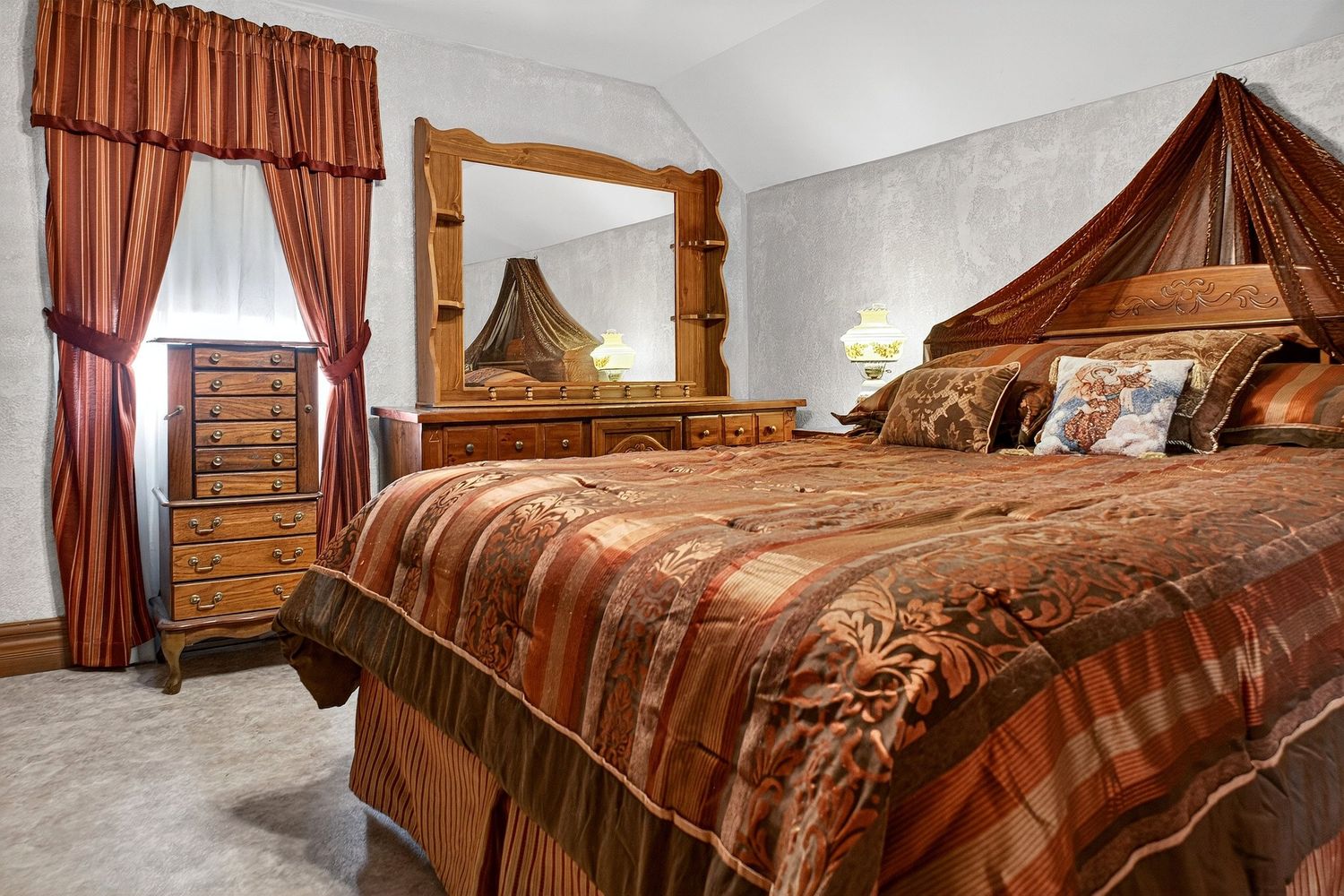 Luxurious bedroom suite with brown bedding, decorative curtains, and warm lighting creating an elegant atmosphere.