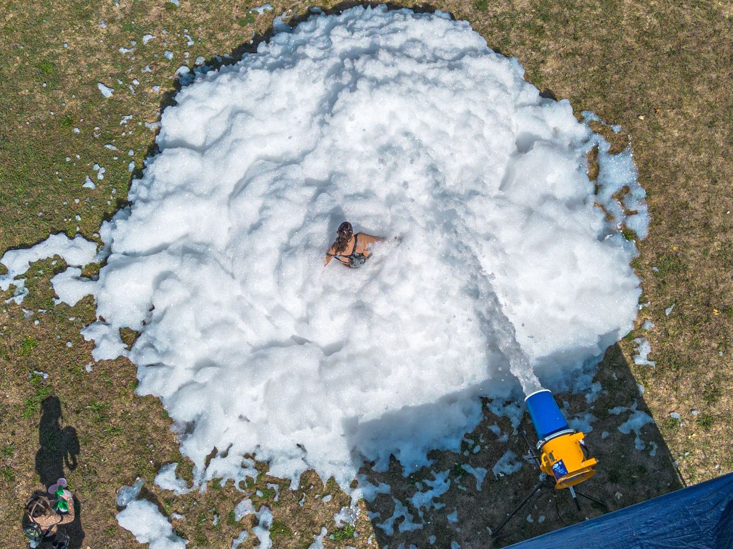 Melting snow patches on brown grass creating abstract patterns viewed from above.