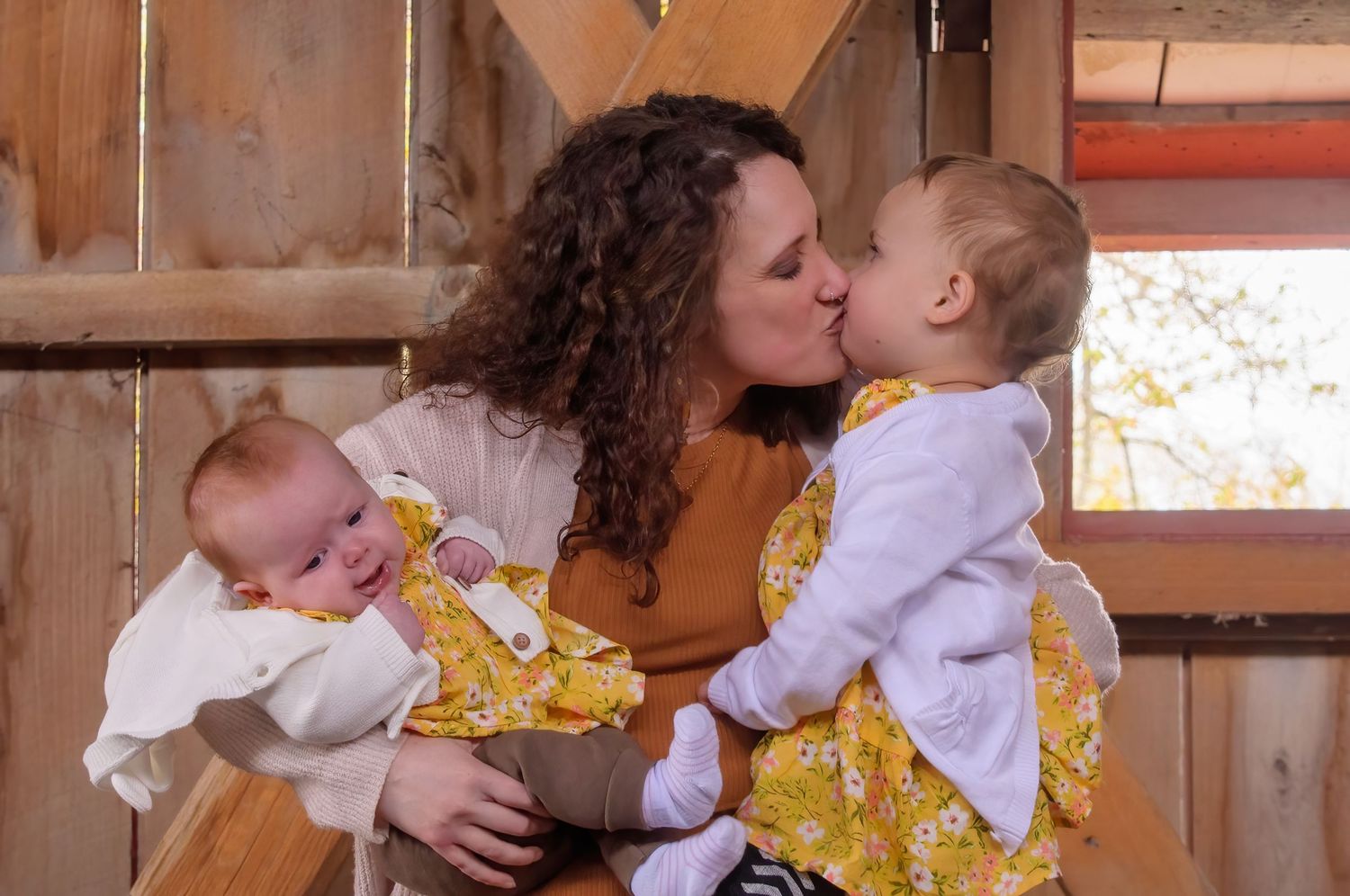 Sweet family moment captured in rustic barn setting with natural lighting.