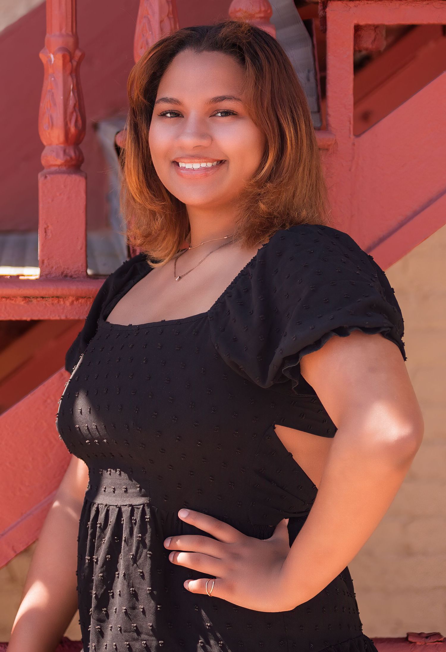 A portrait against a red staircase background on a sunny day.
