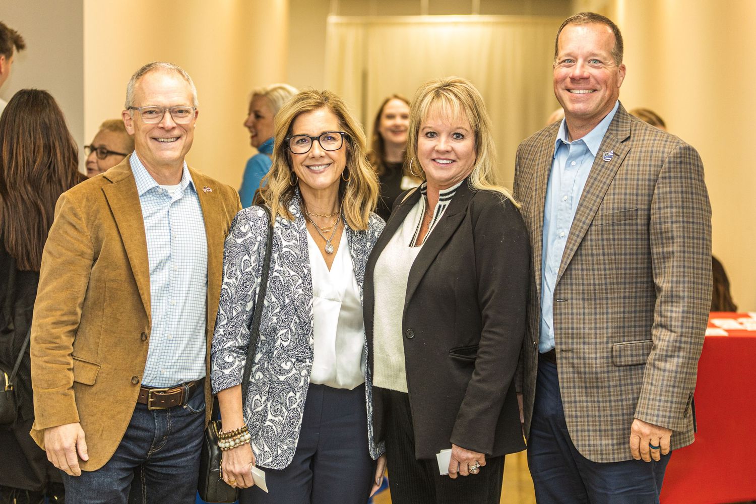 A group of professionals smile together at a formal business gathering.