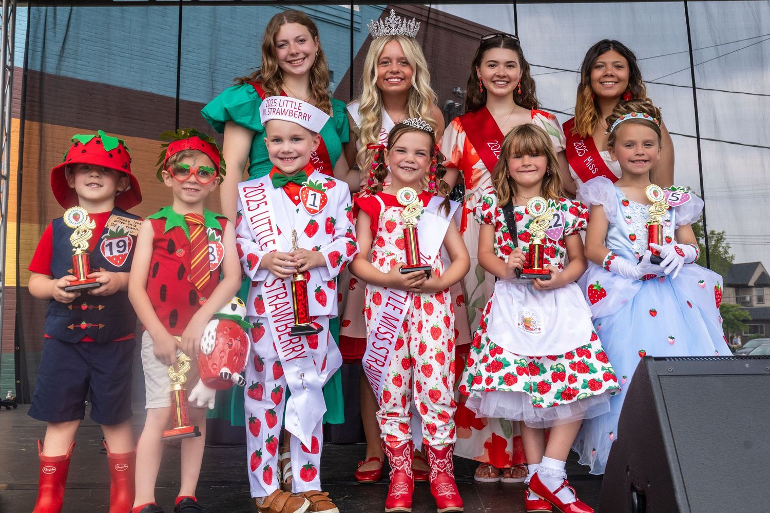Festival participants wearing red and white strawberry-themed costumes gathered on stage.