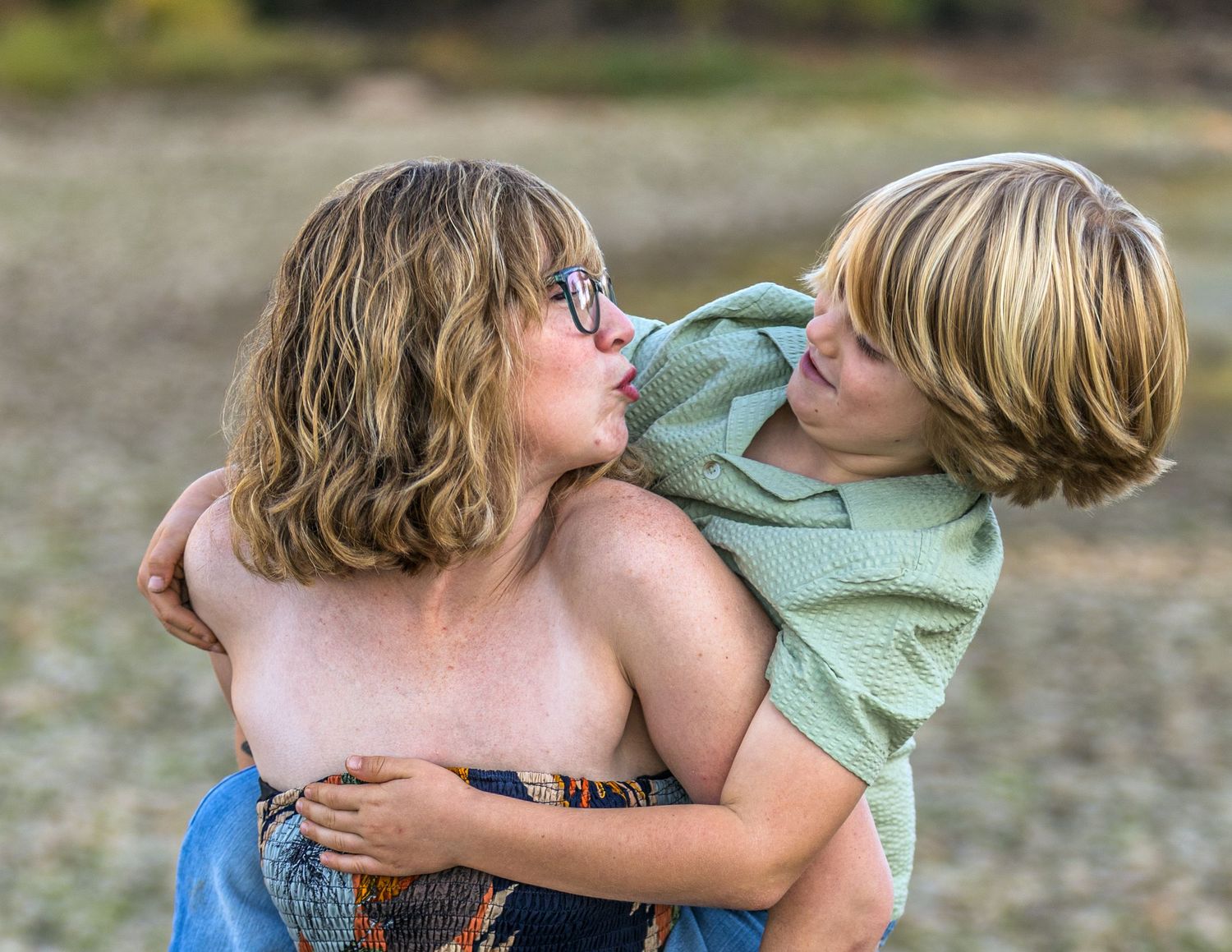 A couple embraces tenderly during an outdoor photoshoot at sunset.