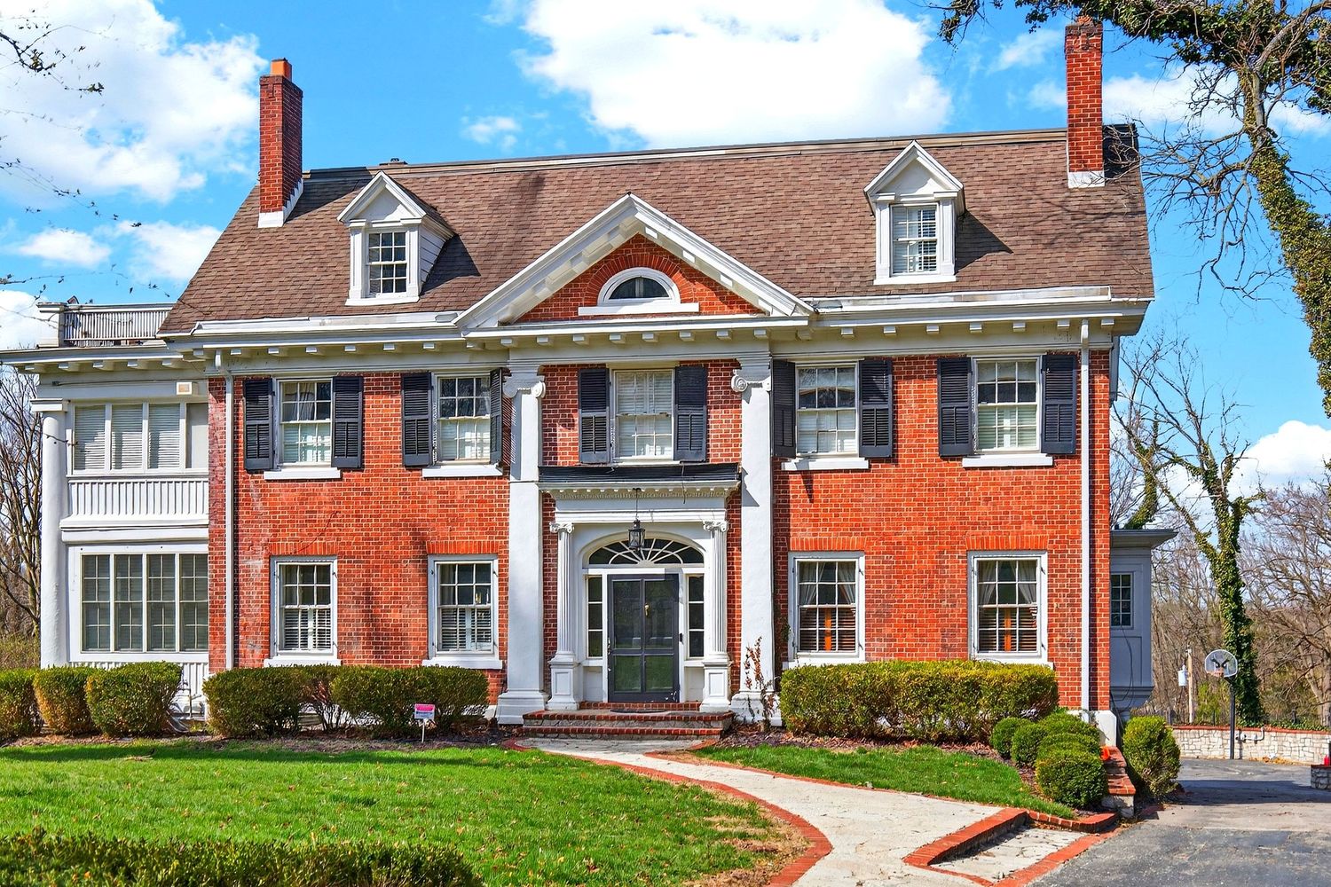 A collection of five traditional red brick colonial style homes with white trim and dormer windows showcases classic American architecture.