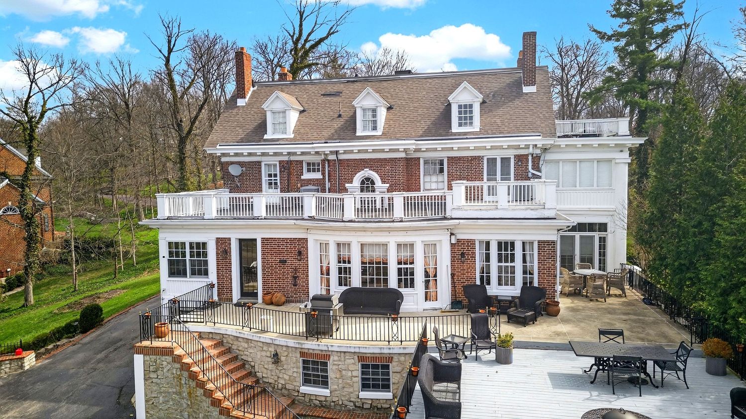 Panoramic view of luxury residential homes with dormers and landscaped yards on a sunny day with blue skies.