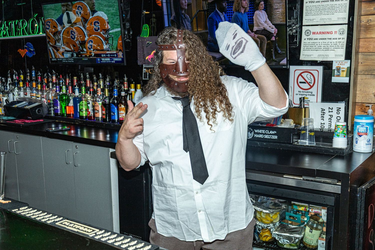 Bar staff in white uniforms posing together behind a counter with liquor bottles.