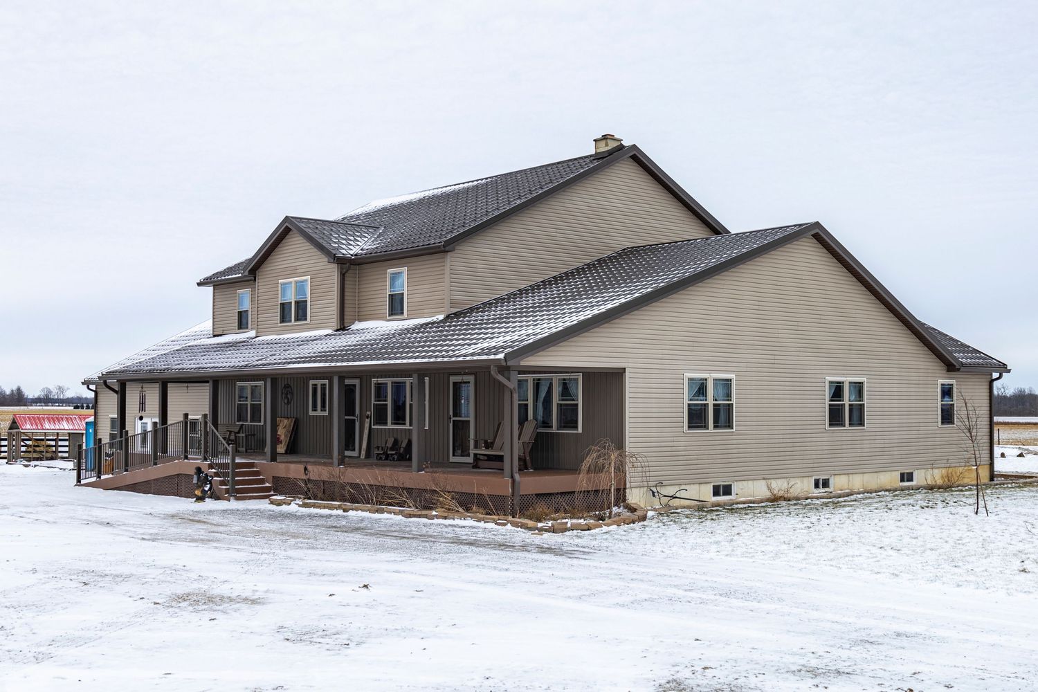Snow-covered ranch house with tan siding stretches across a winter landscape.