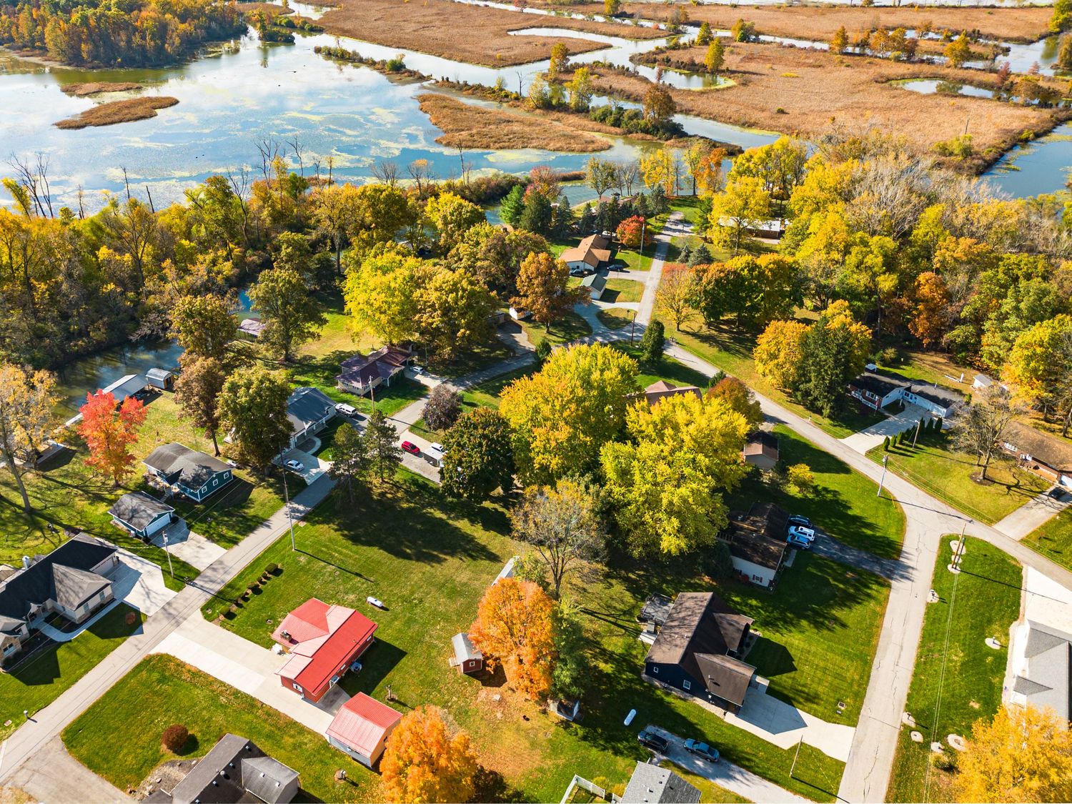 Autumn aerial view of residential neighborhood with colorful trees and winding streets.