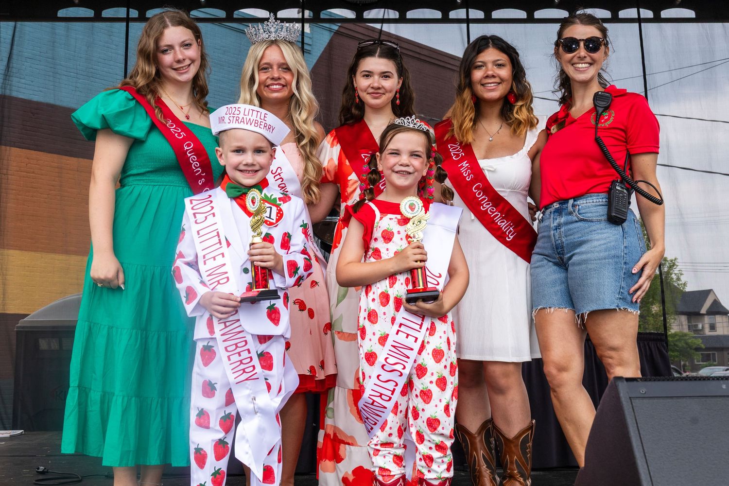 Festival attendees in coordinated strawberry-themed clothing standing together on stage.