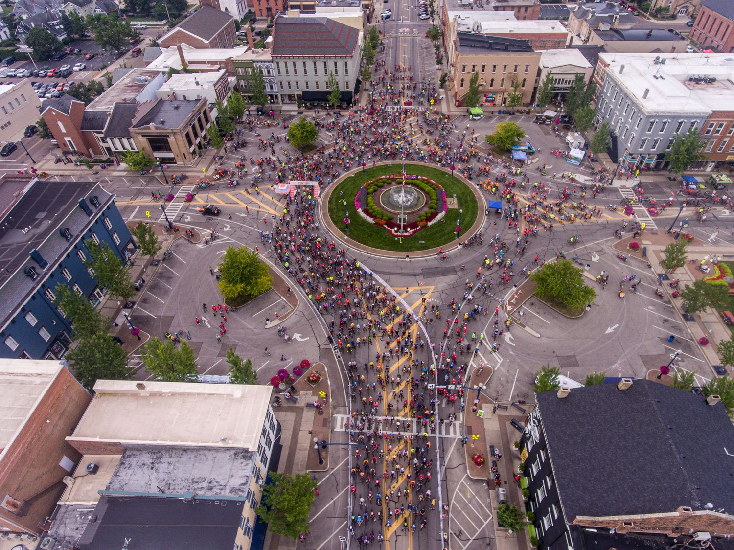 Bird's eye view of city intersection with crowds gathering in downtown area.
