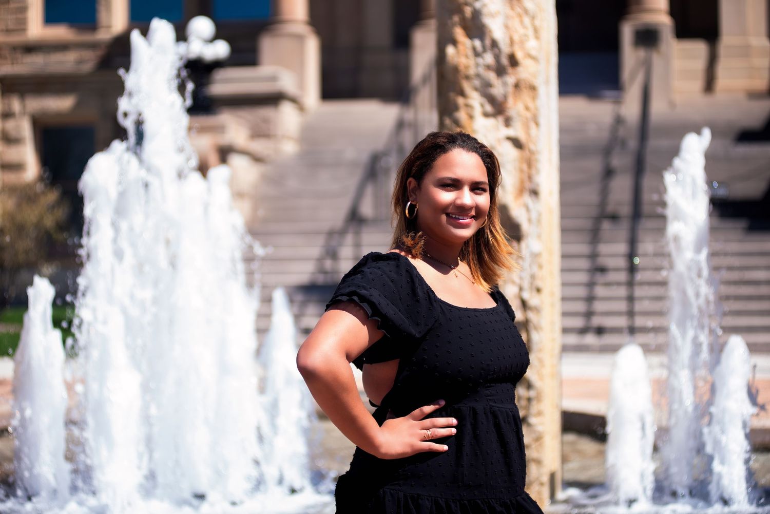 A portrait in front of decorative water fountains at a stone building.