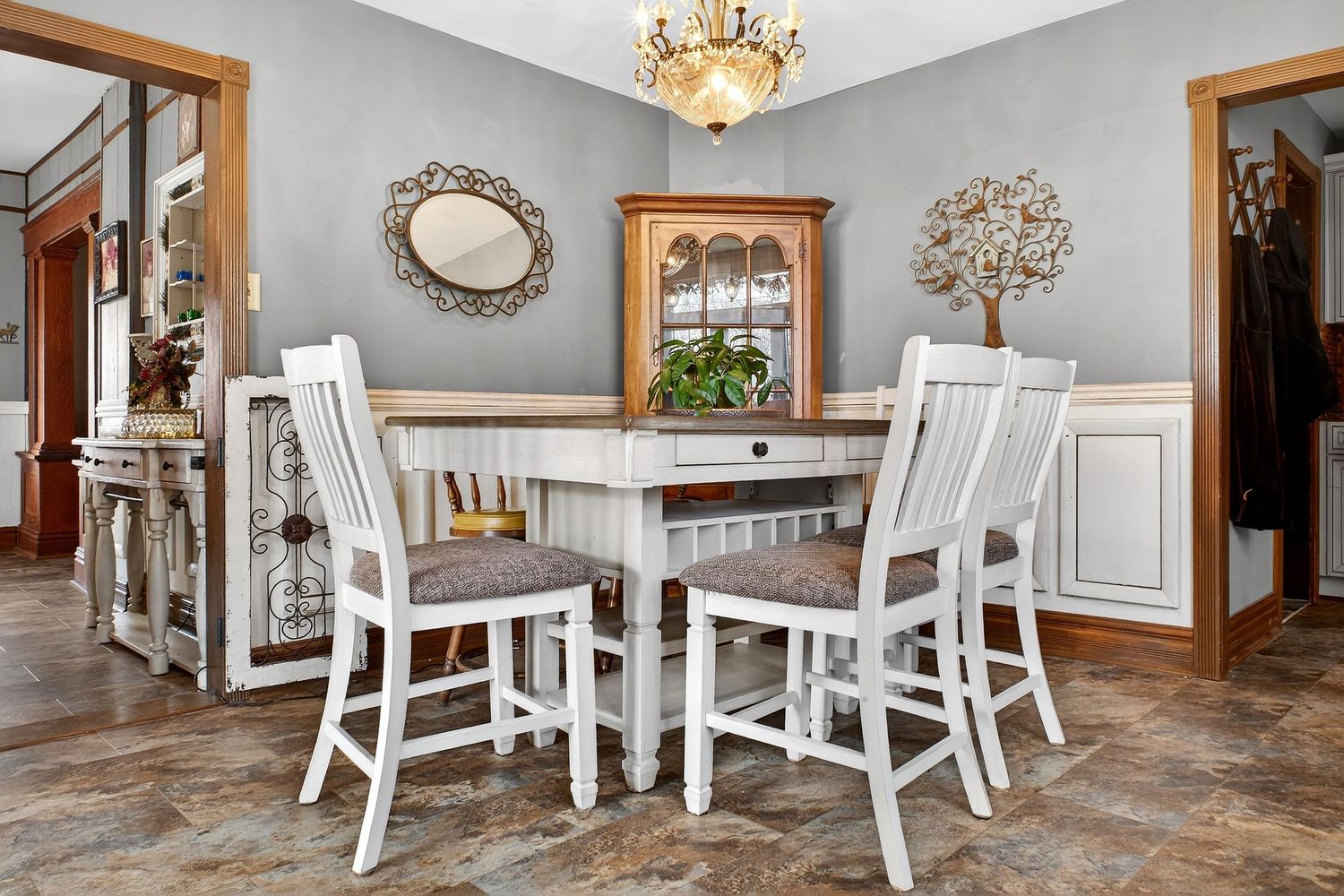 Elegant dining area with white chairs and ornate mirrors featuring classic French country style decor.