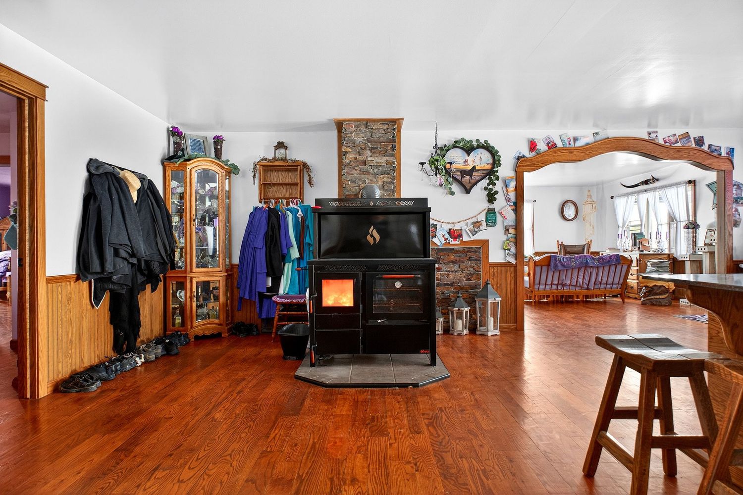 A panoramic view of a modern living room with hardwood floors, stone fireplace, and rustic wooden furniture.