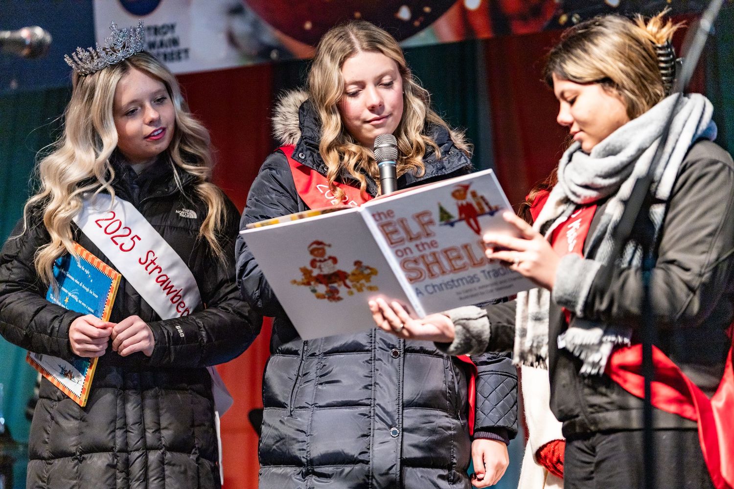 People gathered outdoors reading from books during a holiday event.