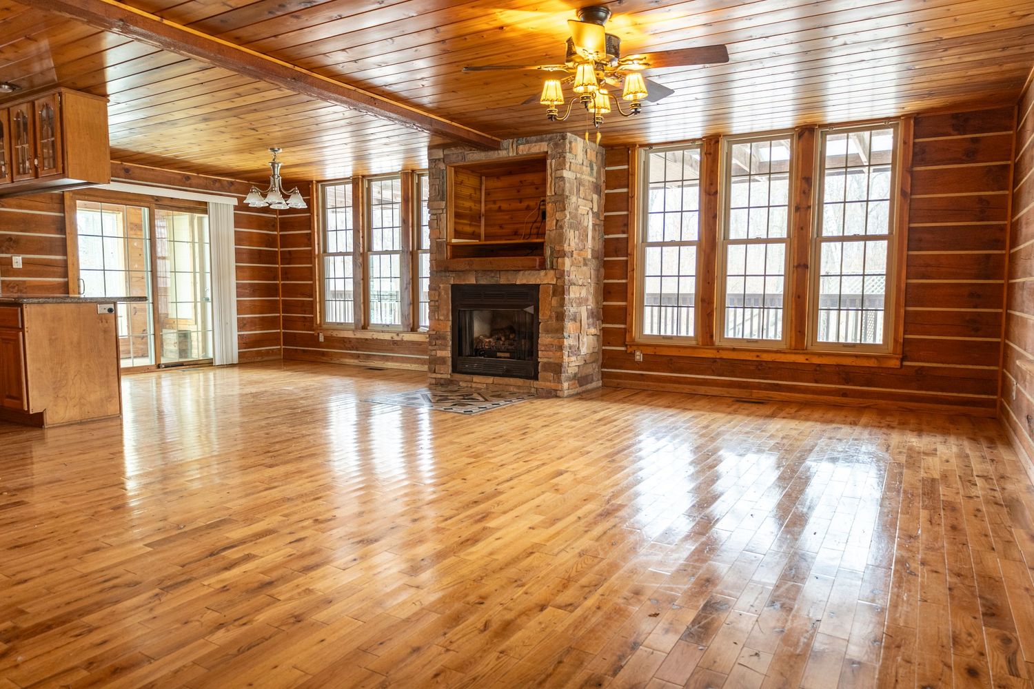 Spacious wooden interior room with vaulted ceiling, hardwood floors and natural lighting.