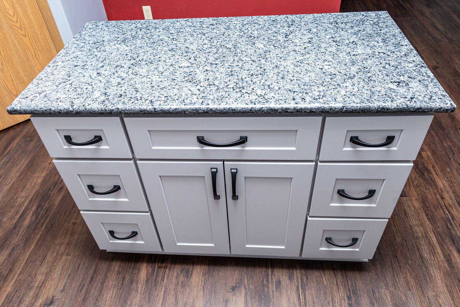 Close-up of white kitchen cabinets with black handles and speckled gray countertops.