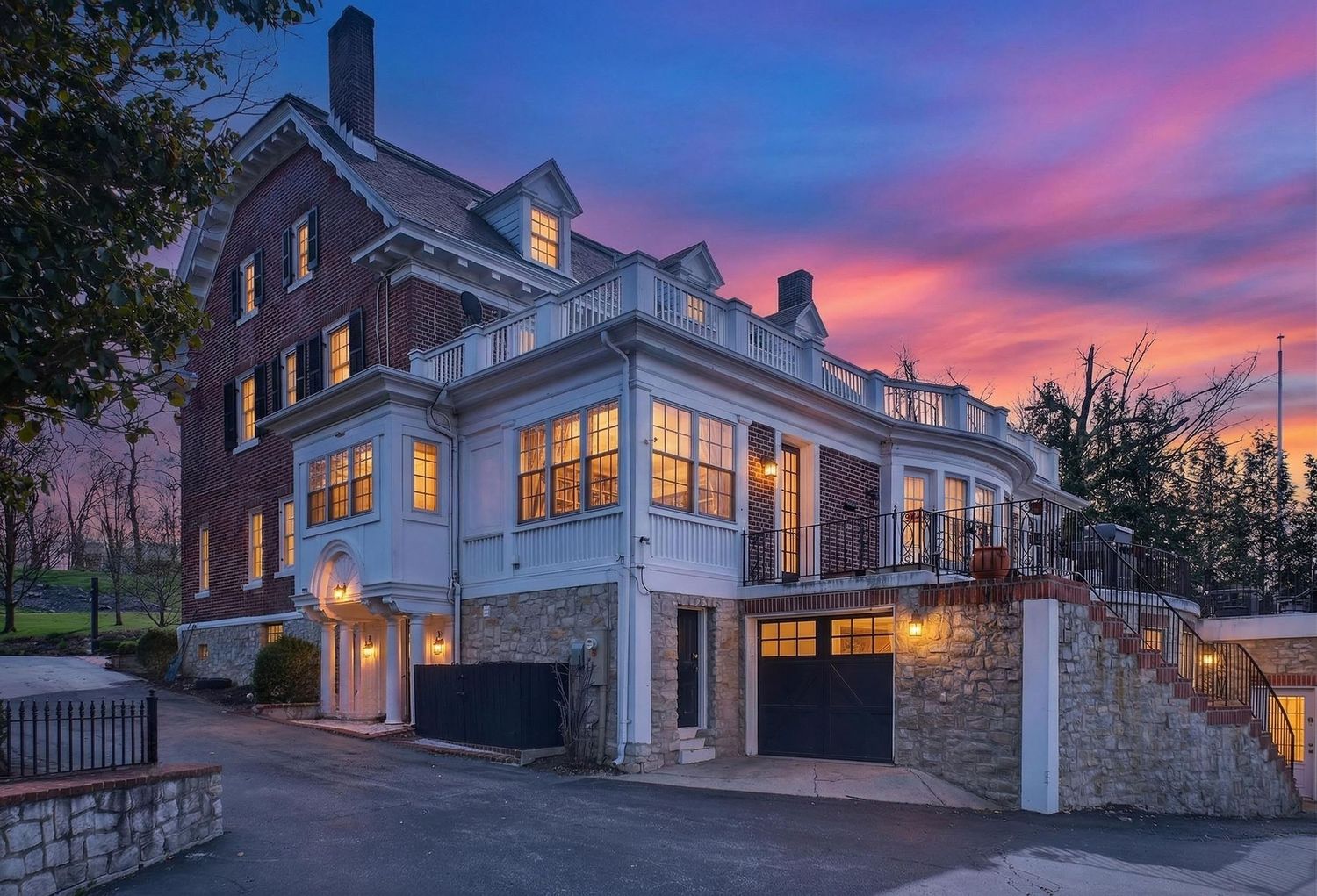 Modern luxury homes with glowing windows at dusk showcase stunning architectural designs against vibrant sunset skies.