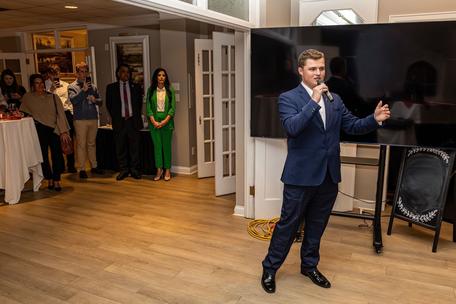 People dancing and performing at formal indoor event with wooden flooring.