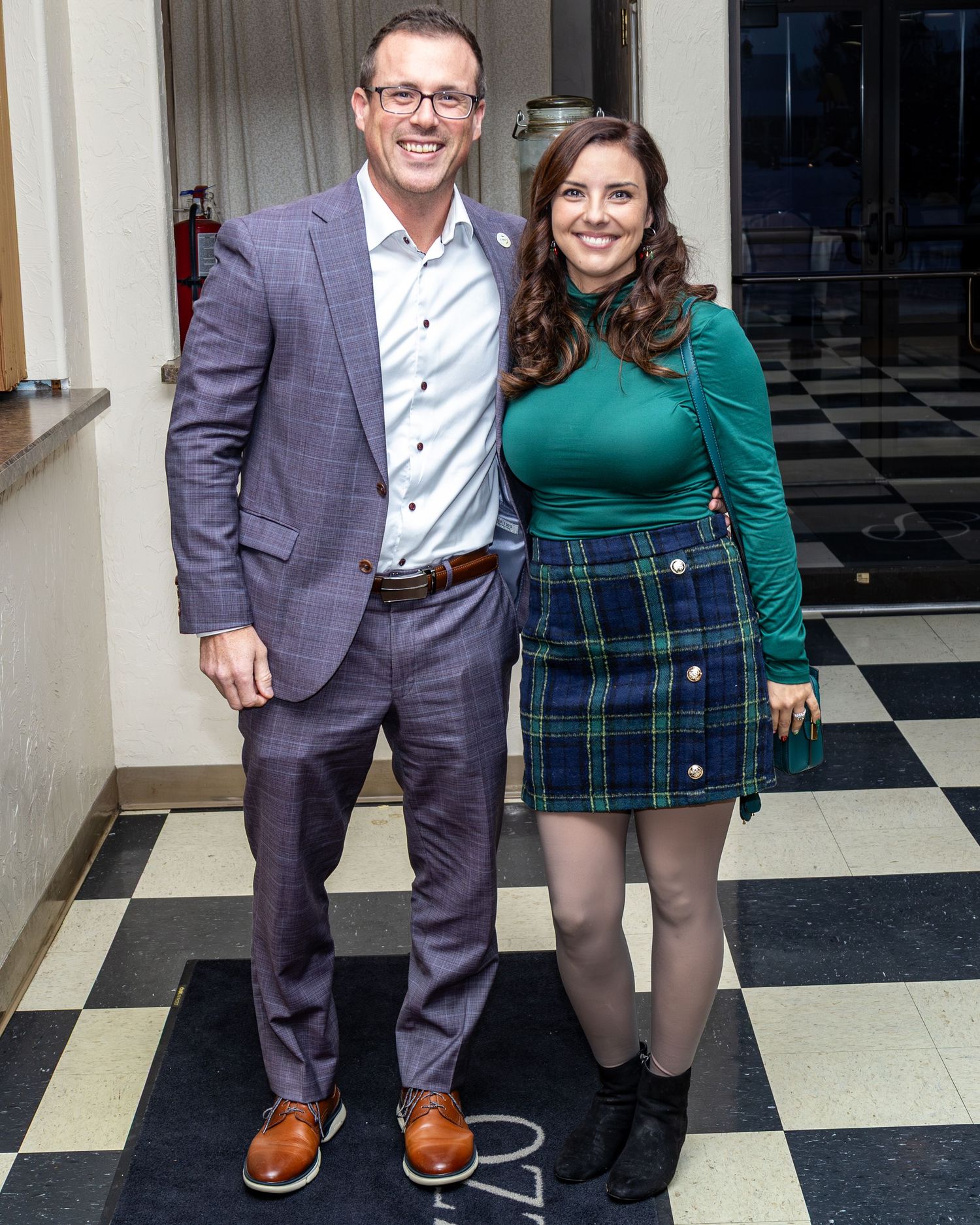 Couple standing on checkered floor wearing formal attire.