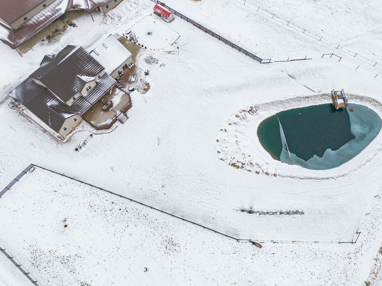 Aerial view of a snow-covered rooftop with a circular skylight and mechanical equipment mounted on the surface.