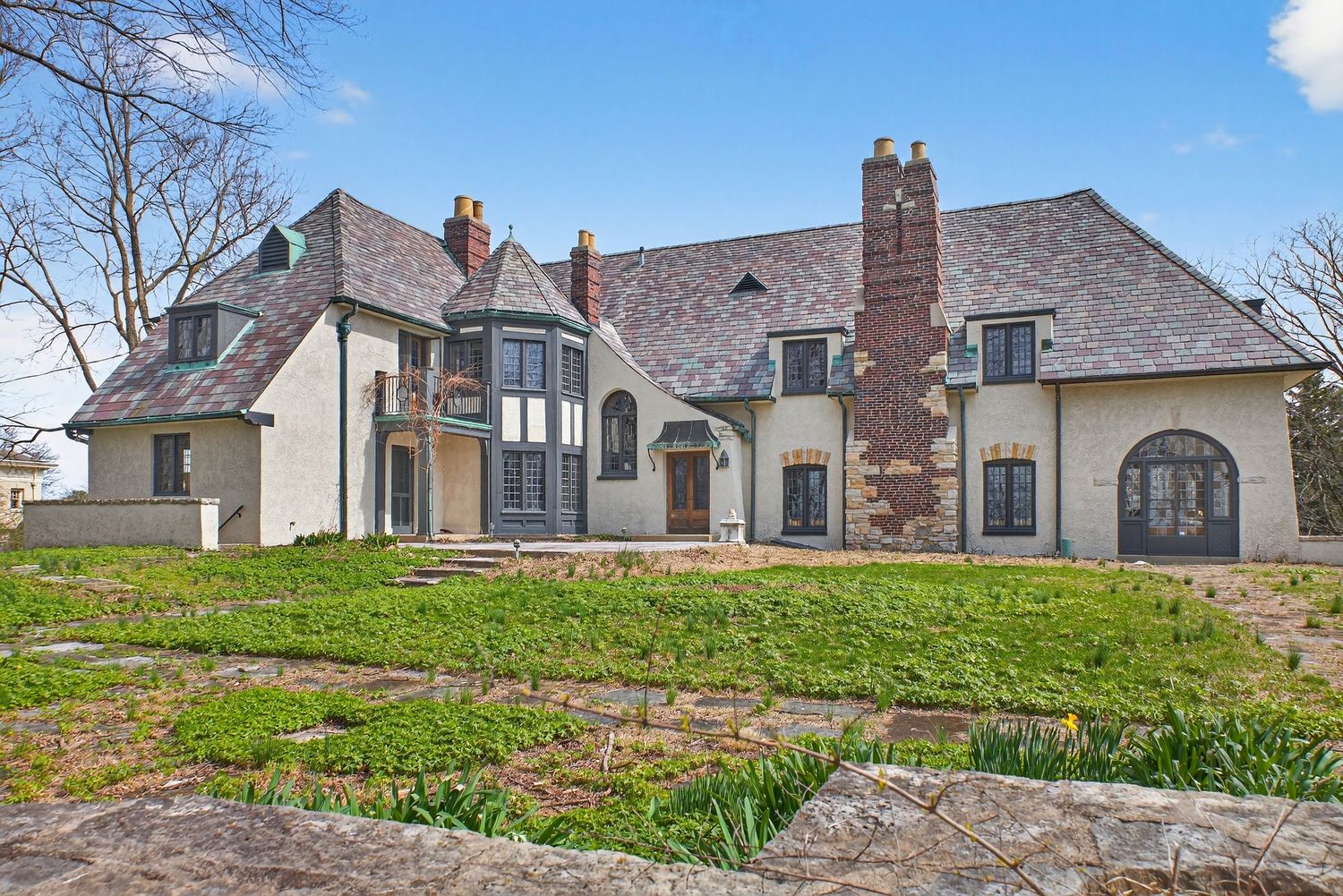 Panoramic view of modern suburban homes with stone facades and landscaped yards on a gently sloping hillside.