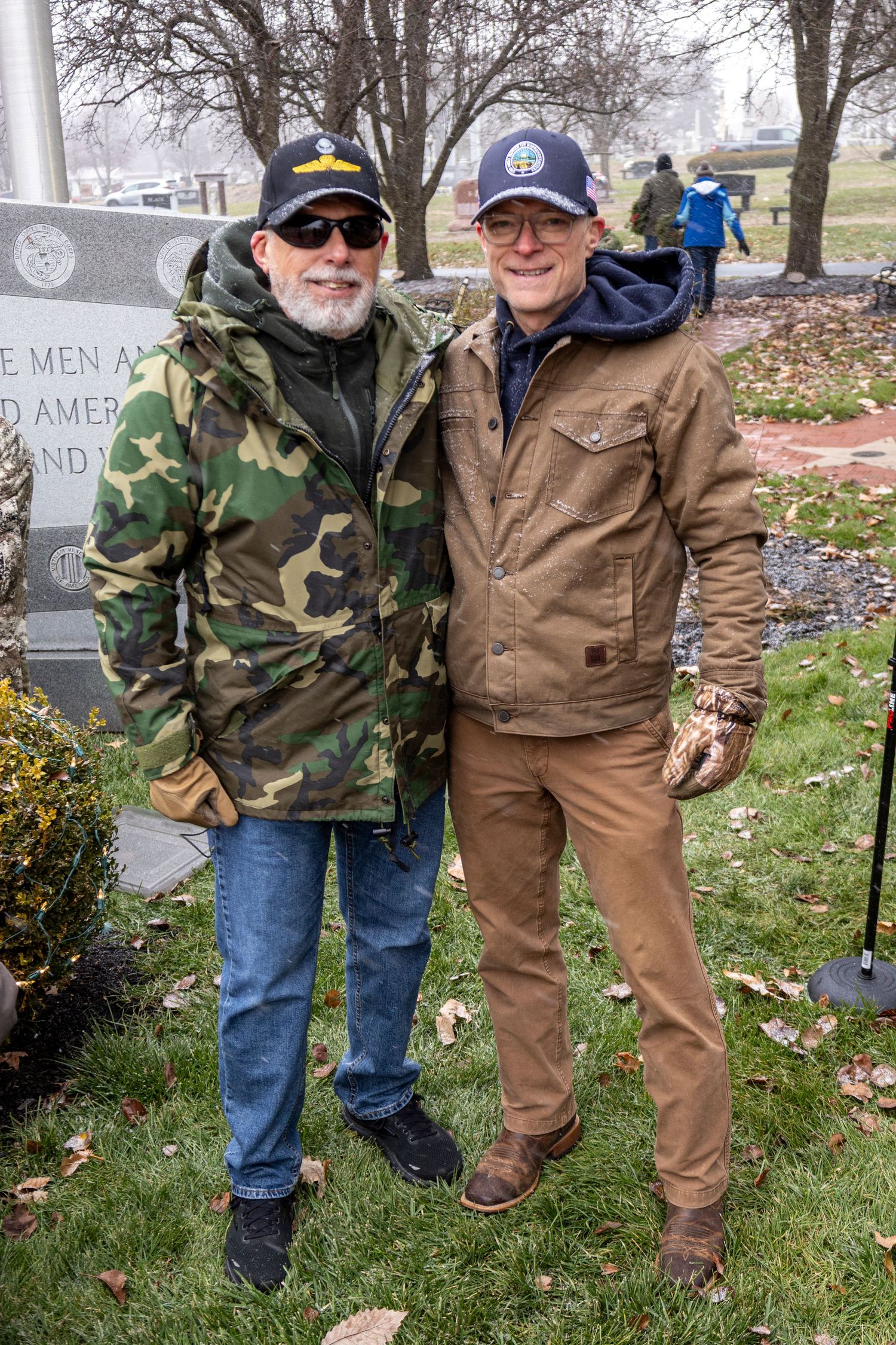 Two veterans in casual attire standing together at a memorial service.