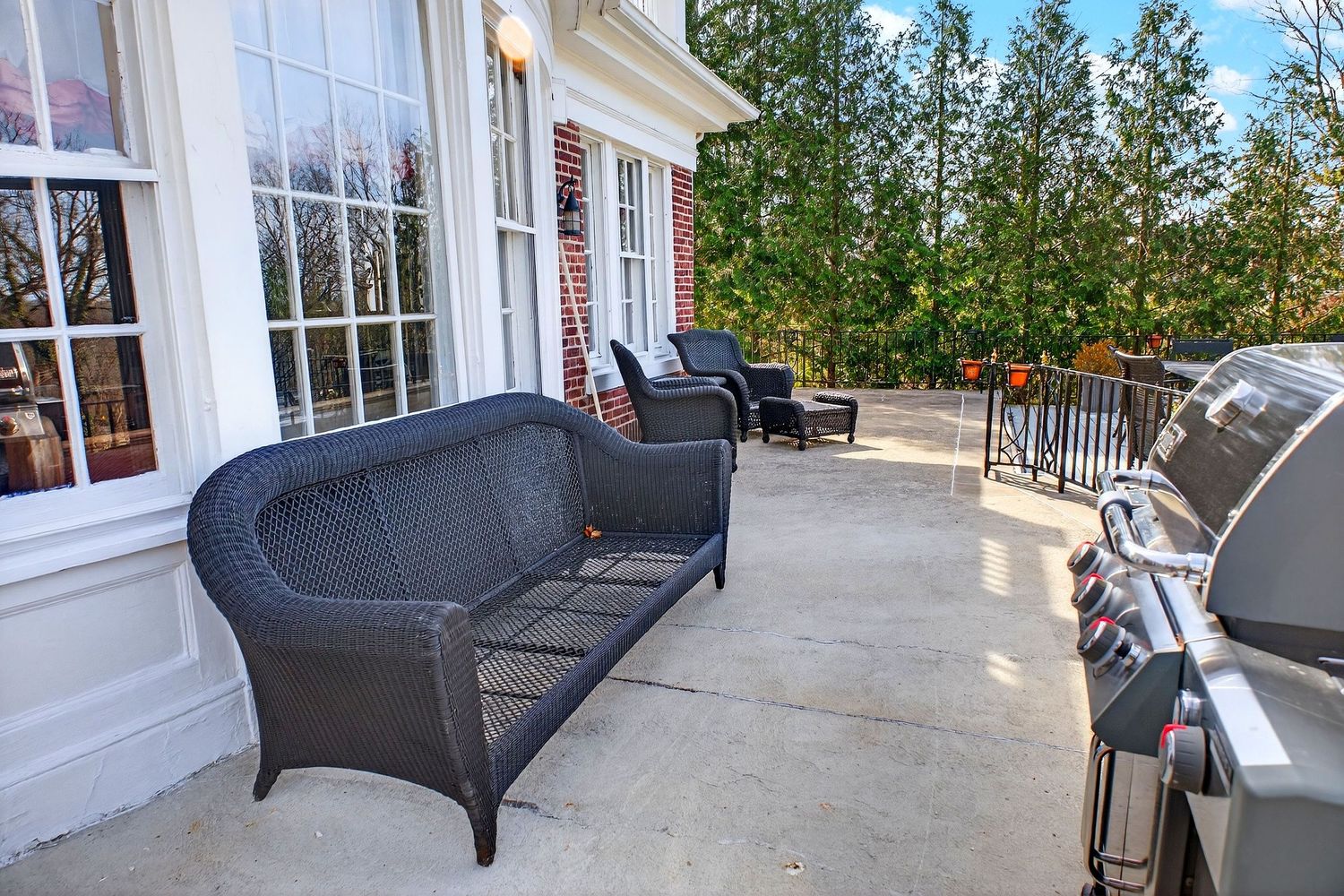 Elegant white porch with wicker furniture and coastal decor showcases a relaxing outdoor living space.