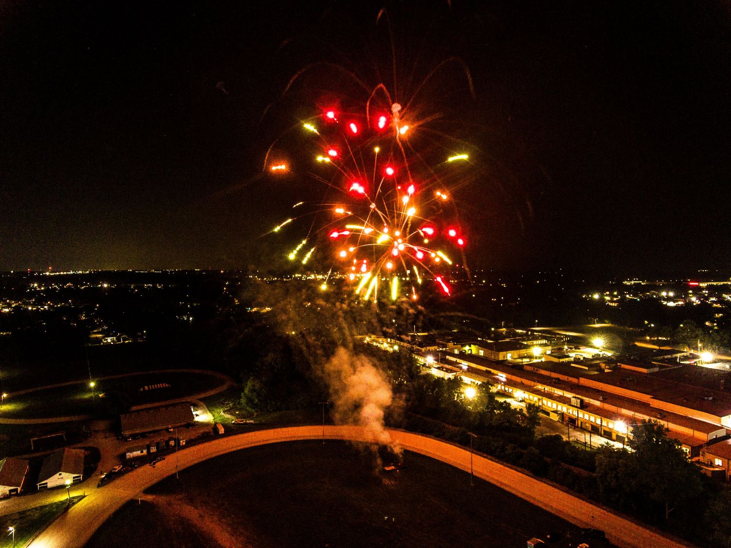 Red and gold fireworks bursting over dark cityscape at night.