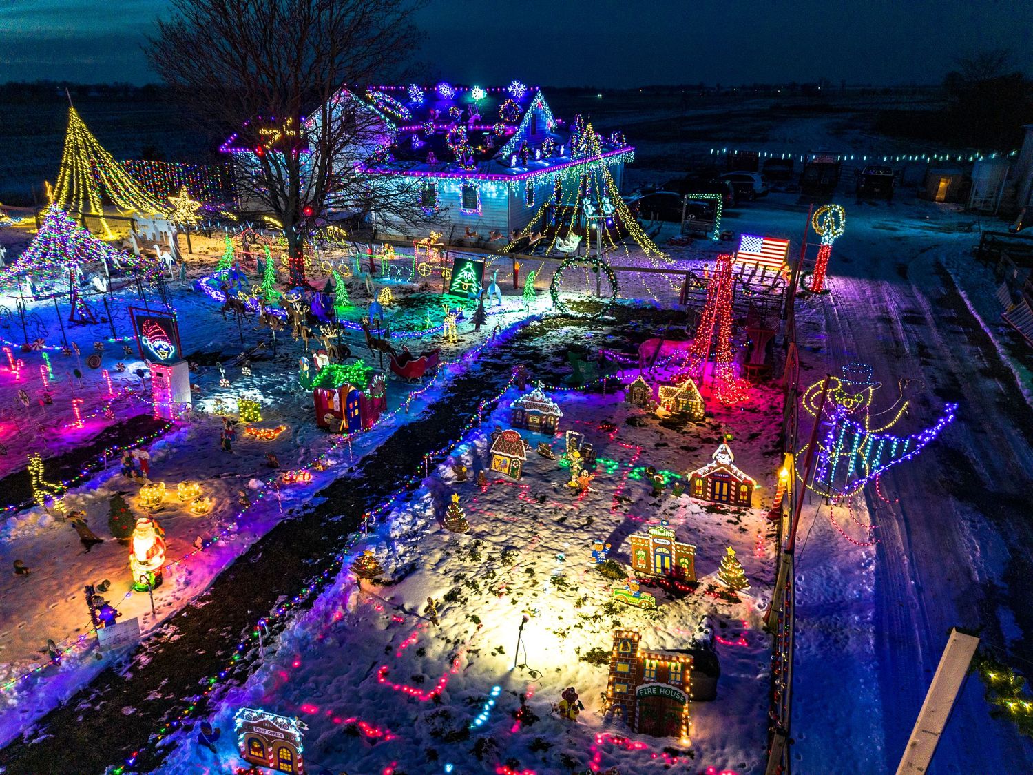 Aerial view of a festive holiday light display with colorful illuminations across a snowy landscape.
