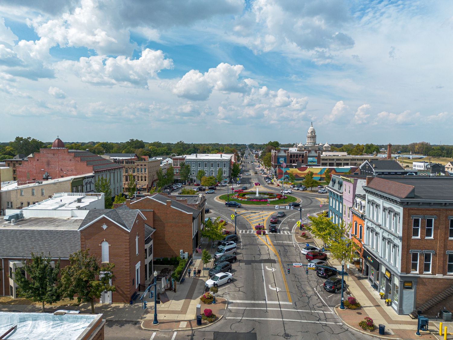 Panoramic cityscape view showing urban streets, buildings and commercial districts under blue sky.