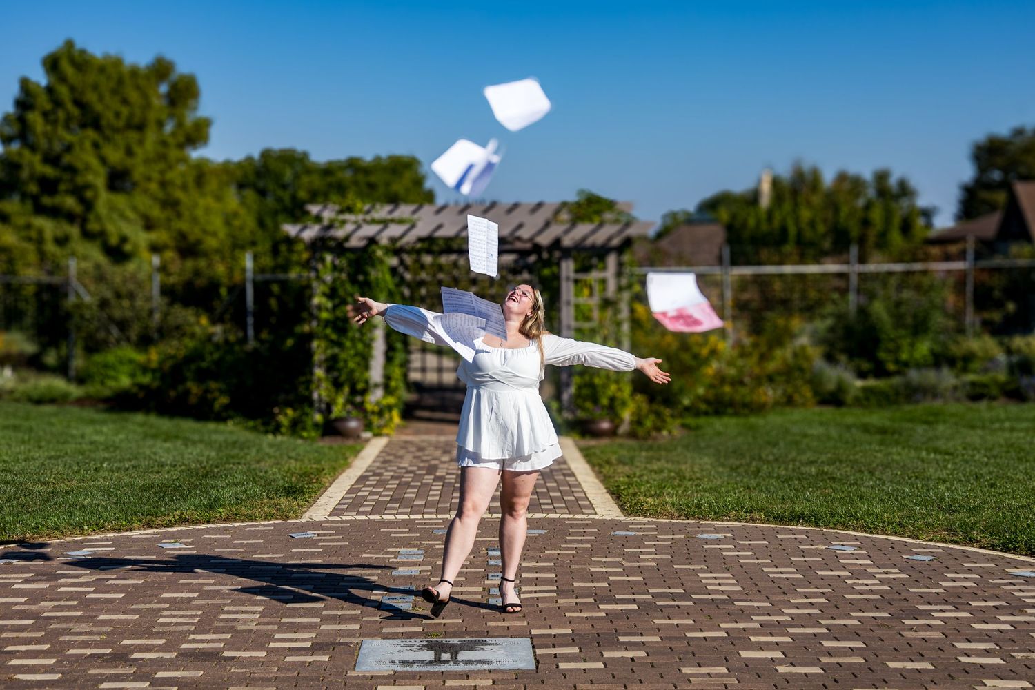 White papers scattered across a brown shingled rooftop against a bright blue sky.