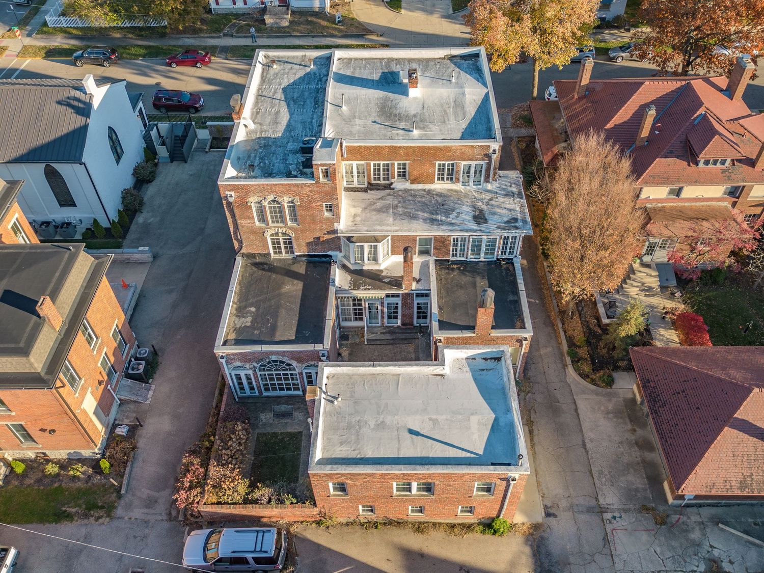 Aerial view of a restored Victorian brick mansion with white trim and multiple balconies.