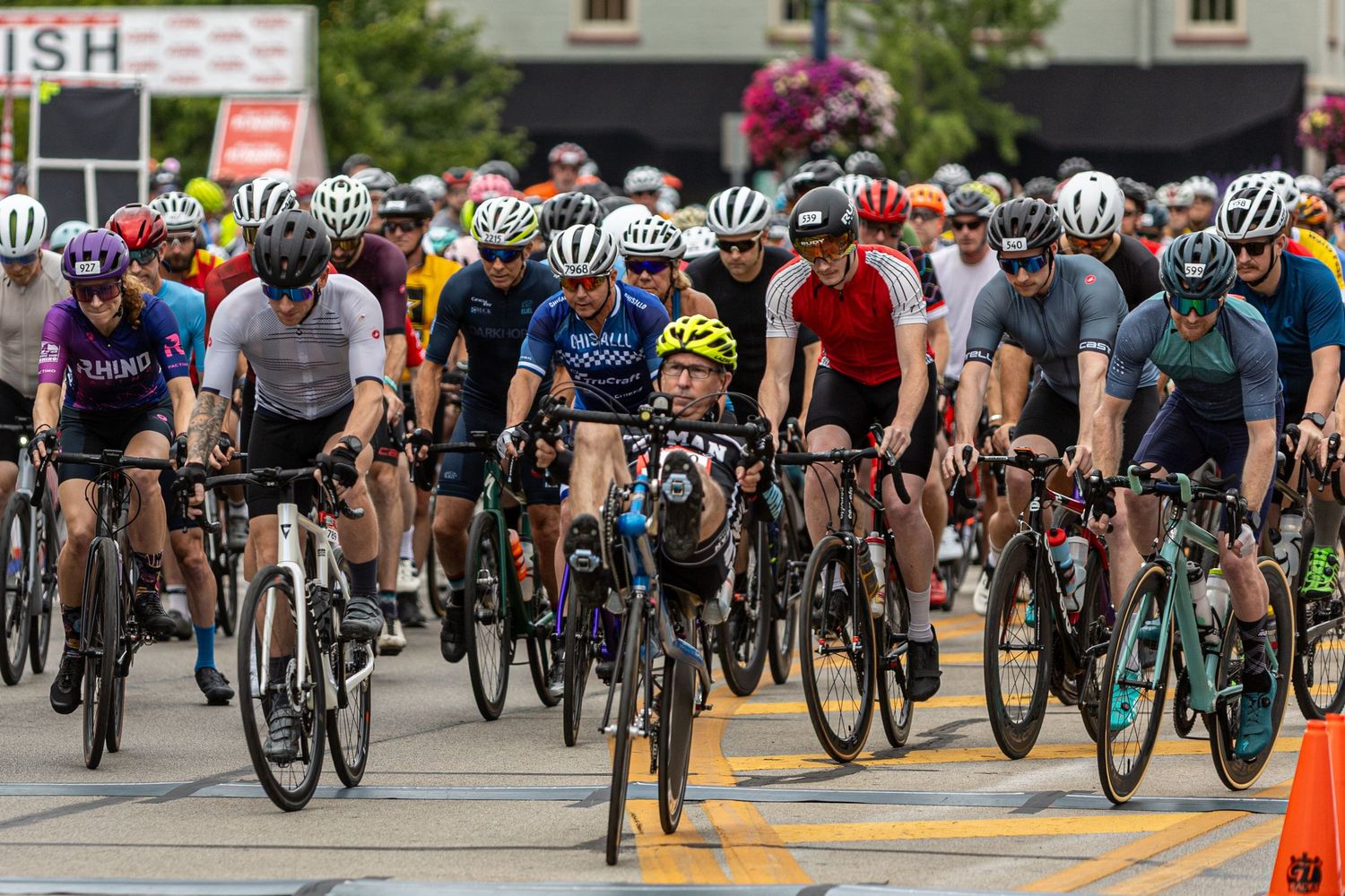 Large group of cyclists lined up at starting line of a bike race event.