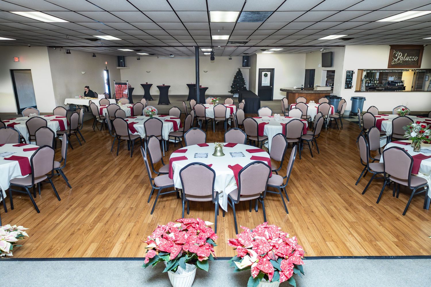 Large banquet hall with pink and white table settings and wooden flooring.