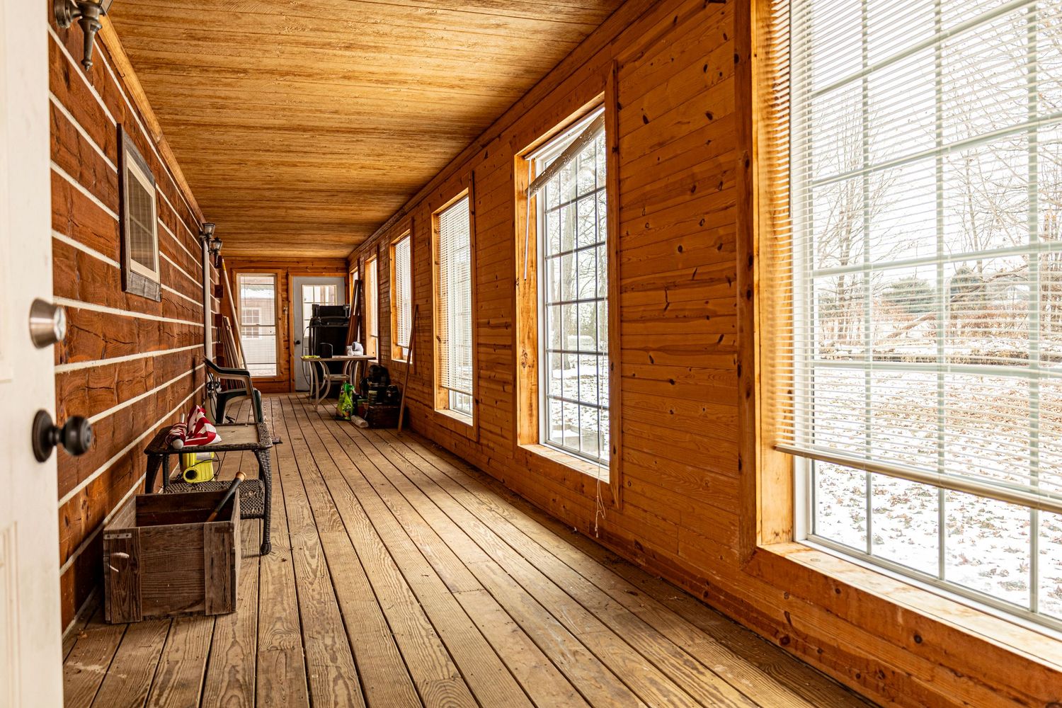 Bright interior hallway of log cabin featuring wood paneling and large windows.