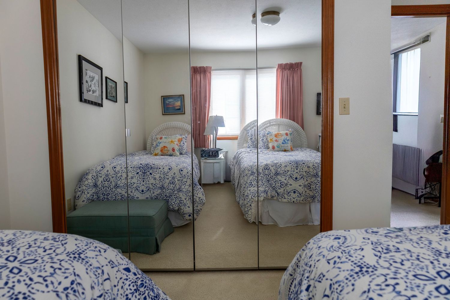 Bedroom with twin beds featuring blue and white floral bedding and mirrored closet doors.
