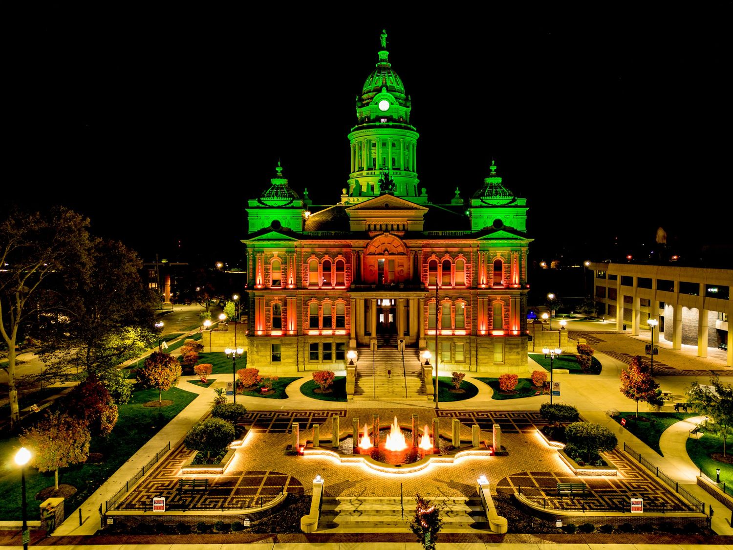 Historic building illuminated in green and red lights for Christmas celebrations.