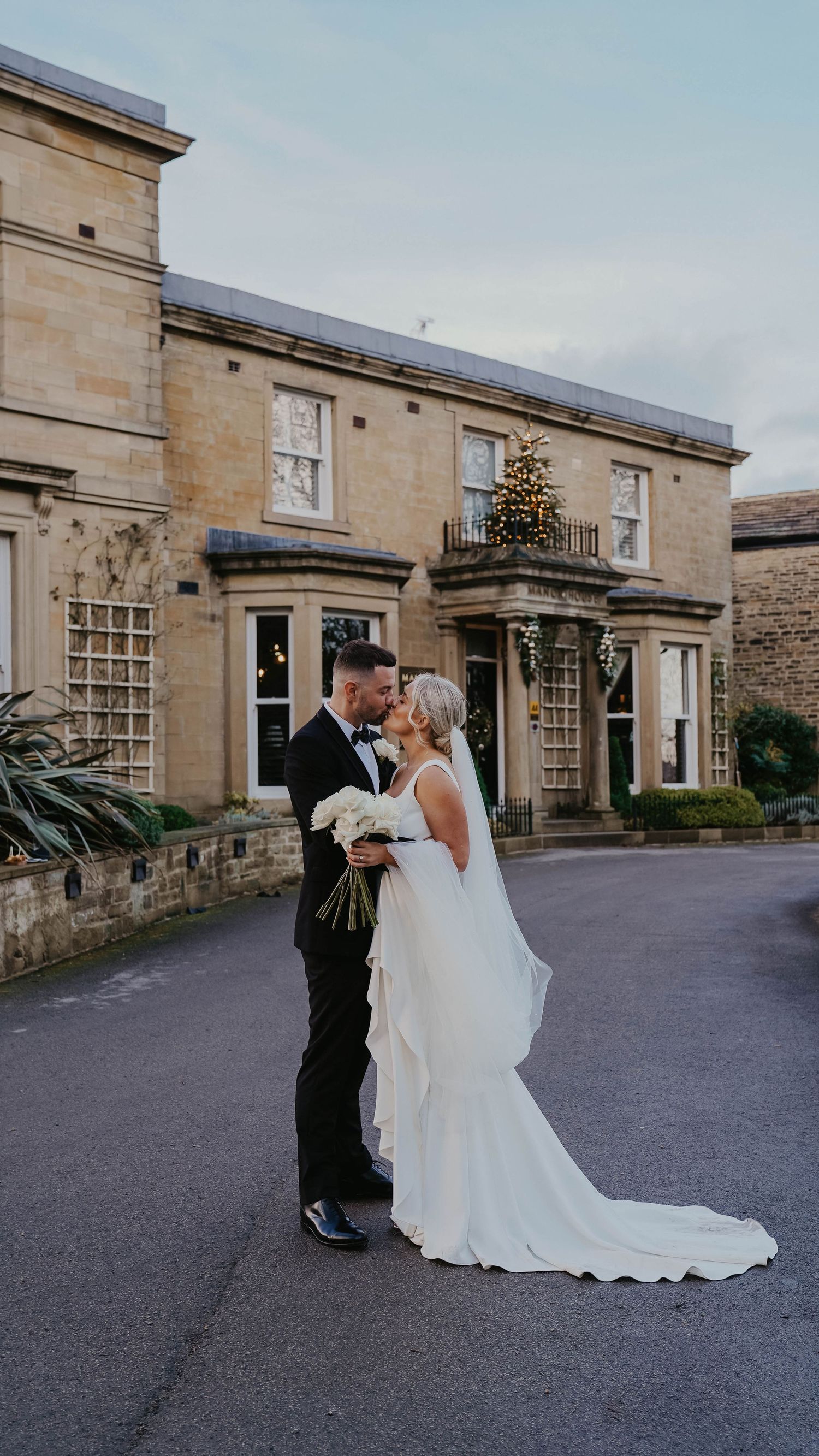 A wedding couple shares an intimate moment outside a grand stone building with a flowing white dress.